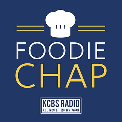 A blue background features a graphic of a white chef's hat above the bold white text "FOODIE CHAP," with "FOODIE" in white and "CHAP" in yellow. Below is the KCBS Radio logo with "ALL NEWS - 106.9FM 740AM" in white text. This design perfectly captures the essence of gourmet cuisine.